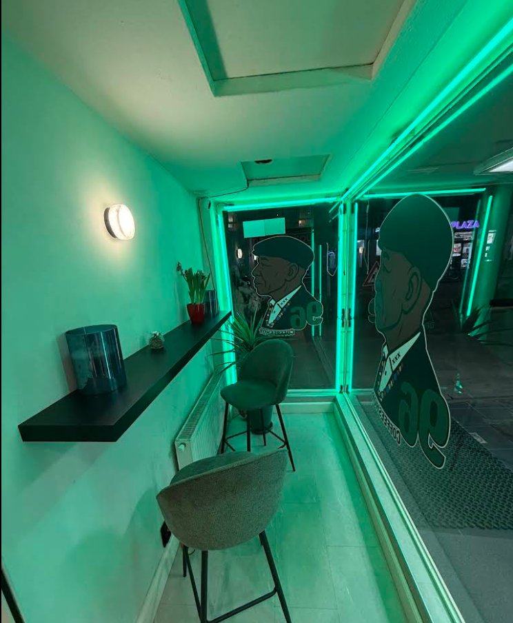 The window bar at Coffeeshop 96 bathed in signature green LED light, with the elder gentleman silhouettes on the window decals